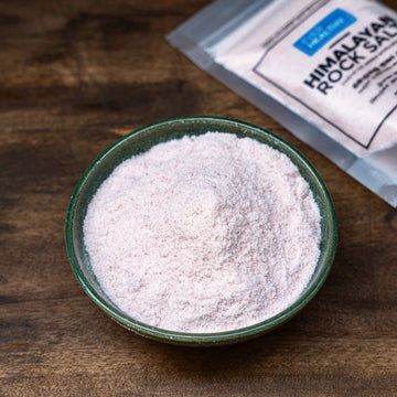Himalayan rock salt in a green bowl on a wooden surface with EverHealthy 400g powder zip lock standup pouch packaging in the background.